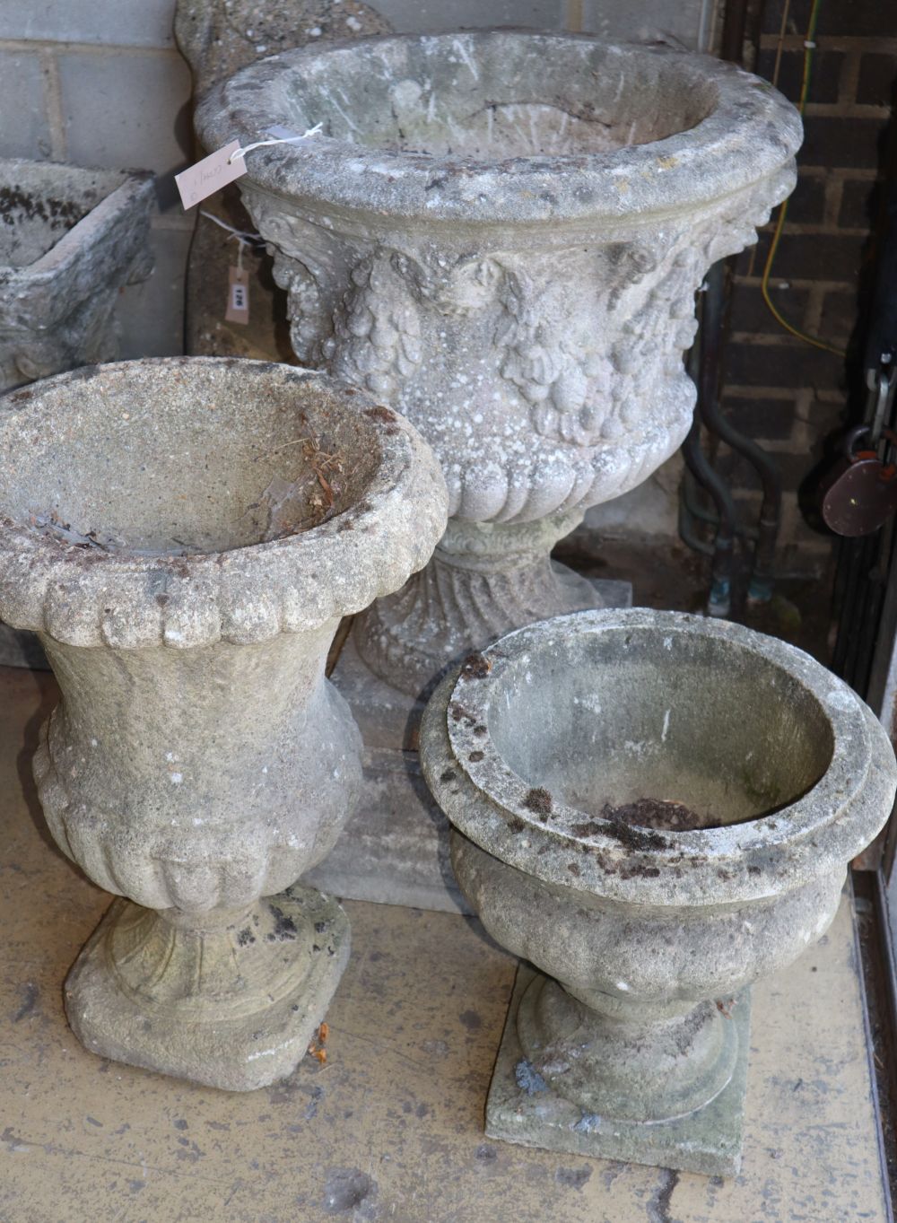 Three reconstituted stone campana garden urns, largest 58cm diameter, H.80cm